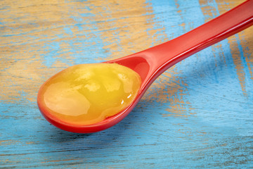 raw honey on a red stoneware teaspoon