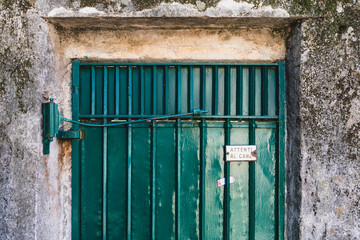 Warning sign Attenti al cane which means beware of dog in Italian attached to green door