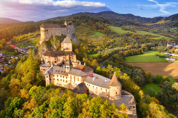 Fototapeta na wymiar Orava castle - Oravsky Hrad in Oravsky Podzamok in Slovakia. Medieval stronghold on extremely high and steep cliff by the Orava river. Aerial view in sunset light