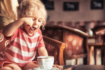 Happy child girl drinking tea in classic traditional English interior restaurant