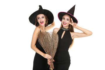 Two young women in black halloween costumes with broom on white background