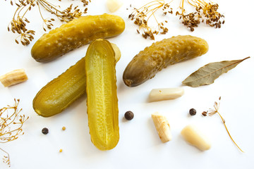 Pickled cucumbers on a white background surrounded by spices