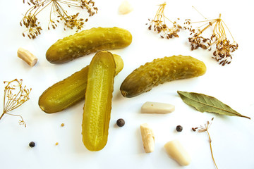 Pickled cucumbers on a white background surrounded by spices