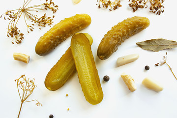 Pickled cucumbers on a white background surrounded by spices