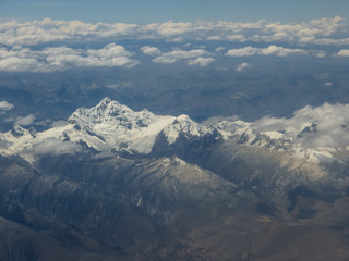 Magestuosa aerial view of large snowy mountains, with glacier, a sunny day with some clouds
