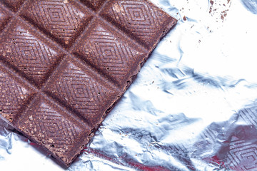 top view porous milk dark chocolate lies on a foil. close-up. Popular dessert.