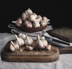 raw unpeeled garlic on a very old vintage cutting board and iron pres
