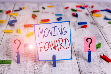 Conceptual hand writing showing Moving Foward. Concept meaning Towards a Point Move on Going Ahead Further Advance Progress Crumbling sheet with paper clips placed on the wooden table