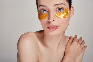 A woman takes care of delicate skin around her eyes. Cosmetic procedures. Facial skin care.