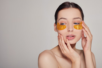Mask for removing wrinkles and dark circles. A woman takes care of delicate skin around her eyes. Cosmetic procedures.