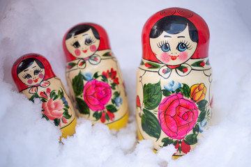Three Traditional russian wooden nesting dolls Matryoshka buried in the real glittering snow.