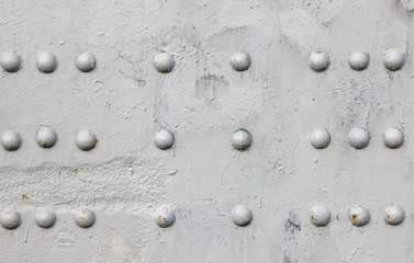 Riveted with button-head rivets metal plate (detail of a bridge) painted in gray as a background
