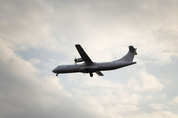Airplane flying in the sky against a background of  clouds at sunset