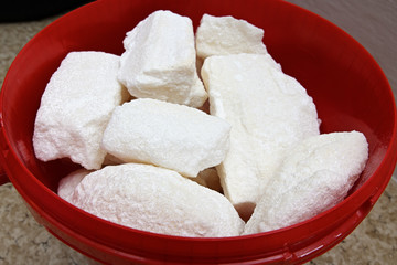 Lumps of sugar in a red plastic bucket.