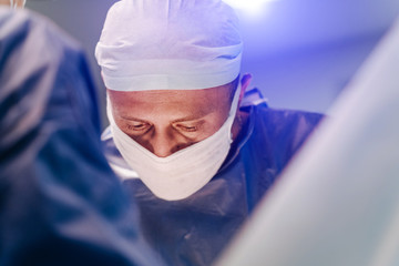 Process of surgery operation using medical equipment. Surgeon in operating room with surgery equipment. Medical background. Closeup of a doctor in medical mask.