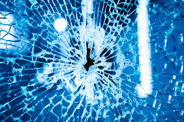 Broken glass window. Blue background. Closeup.