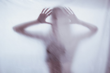 silhouette of a female sexual figure behind foggy glass. concept of the spirit of poltergeist from...