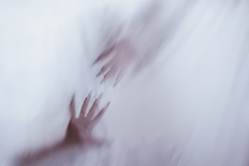 silhouette of a female sexual figure behind foggy glass. concept of the spirit of poltergeist from the other world. frightening hands of death through the fabric.