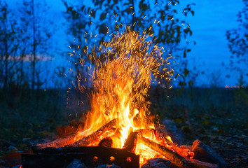 Red fire flame in dark evening on blue background.