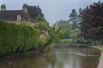Fototapeta na wymiar BOURTON-ON-THE-WATER, COTSWOLDS, UK - MAY 28, 2018: Stone footbridge across the River Windrush in Bourton-on-the-Water, also known as The Venice of the Cotswolds - Gloucestershire - England -UK