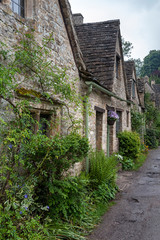 Fototapeta na wymiar BIBURY, COTSWOLDS, UK - MAY 28, 2018: Traditional cotswold stone cottages built of distinctive yellow limestone in the world famous Arlington Row, Bibury, Gloucestershire, England 