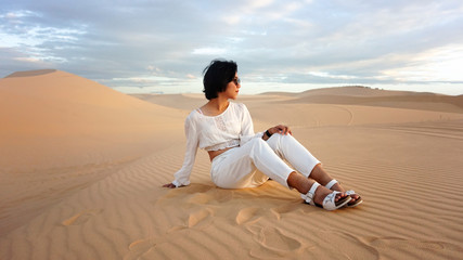 Fototapeta na wymiar A girl siting in desert, There are sand and cloud behide hers.
