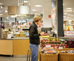 Young man shopping in supermarket, reading product information