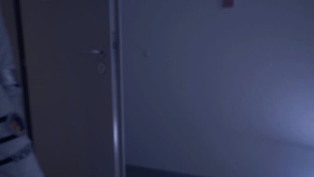 Tight close up cinematic footage of an astronaut entering a door in slow motion with his spacesuit material and kevlar in focus while walking past a corridor 4K