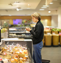 Young man shopping in supermarket, reading product information
