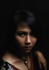 Naklejka premium Asian short black haired woman Wearing jewelry made of leather and stone On her face, there is a small freckle On a black background and shadows