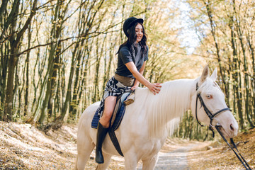 Obraz premium beautiful young girl riding a horse in the autumn forest