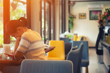 Atmosphere in a restaurant or coffee shop With chairs and tables for customers There are women who are serious with her mobile phone. And orange light from the window