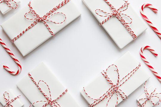 Flat lay composition with Christmas gifts boxes with red ribbon, candy canes on white background, copy space. Winter holiday pattern. Top view