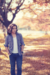 Asian long hair man Walking in the garden The background is a tree and the sunlight in autumn.