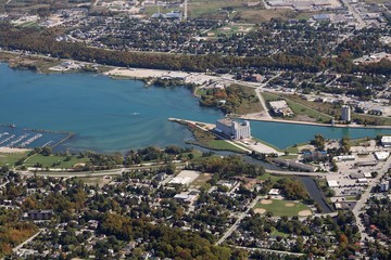 Looking down small plane at blue water of Georgian Bay and grain elevators  houses and streets at the mouth of the Owen Sound harbor