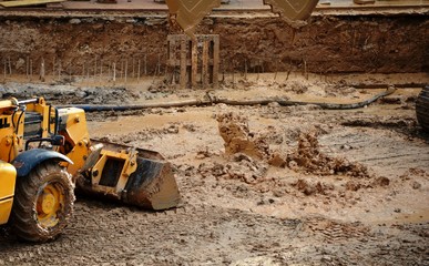 una excavadora y una grúa con cuchara mecánica recogiendo barro