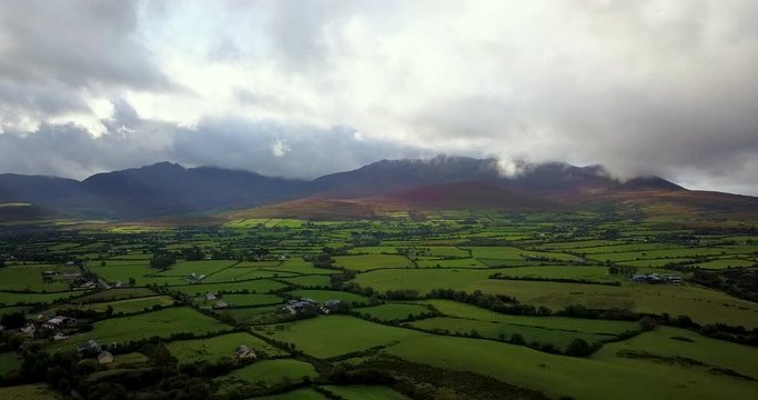 drone footage of the landscape and mountains surrounding killarney national park in autumn showing cloudy skies and green fields
