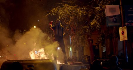 Young rebel resolutioner and anarchist stands on trash and fire and showing fuck as a protest for independence of a demonstration about the proces and political prisoners. Demonstrator burns garbage