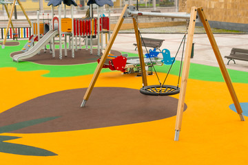 Empty playground with swings and safe rides with anti-traumatic bright rubber crumb coating