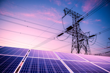 Solar photovoltaic panels and transmission towers at sunset. Alternative power sources - the...