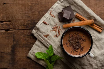 Fototapeten Tasse heiße Schokolade, Zimtstangen, Minze und Schokolade auf Holztisch © Anton