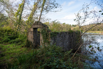 Fototapeta na wymiar Dilapidated abandoned stone building by lake