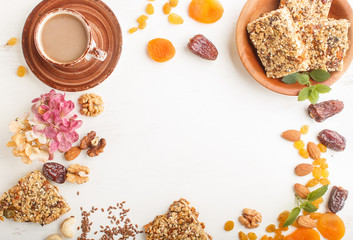 Homemade granola from oat flakes, dates, dried apricots, raisins, nuts with a cup of coffee on a white wooden background. Top view, frame.