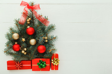 Fototapeta na wymiar Xmas New Year pattern composition: Christmas Tree made from fir branches, red gift boxes on white wooden background, concept of holiday celebration 2020. Flat lay, top view, copy space.