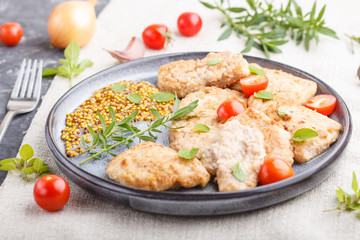 Fried pork chops with tomatoes and herbs on a gray ceramic plate on a black concrete background. side view, selective focus.