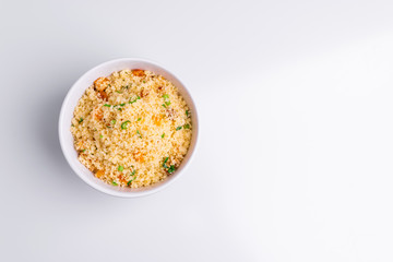 Delicious homemade vegetarian couscous with dates, raisins, parsley, tomato, lemon and olive oil in a white bowl on white background, Traditional Moroccan and Arabic Salad Tabbouleh