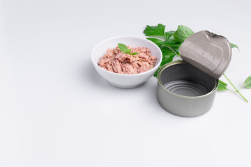 Canned tuna in a white bowl, isolated on white; empty open tuna tin on a white background; copy space, soft light, studio shot