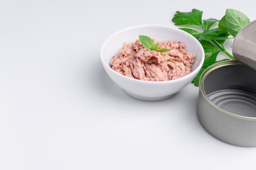 Canned tuna in a white bowl, isolated on white; empty open tuna tin on a white background; copy space, soft light, studio shot