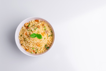 Delicious homemade vegetarian couscous with dates, raisins, parsley, tomato, lemon and olive oil in a white bowl on white background, Traditional Moroccan and Arabic Salad Tabbouleh