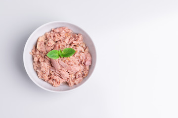 Canned tuna in a white bowl, isolated on white background; copy space, soft light, studio shot